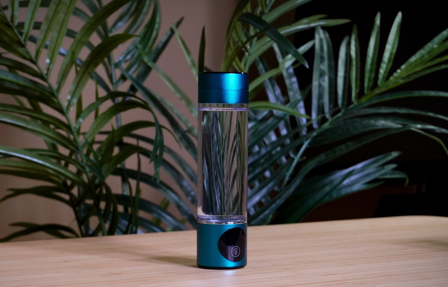 Hydrogenflaske placeret foran frodige tropiske planter, fremhæver produktets miljøvenlige tilgang og stilrene, moderne design